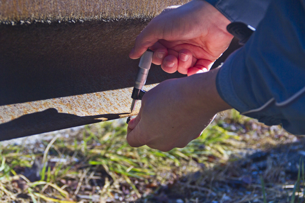 Hands placing a metal bolt in a railway track