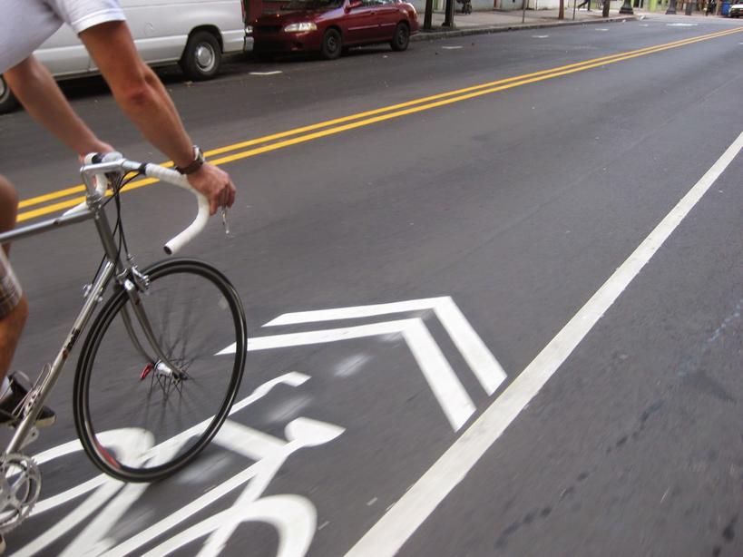 blurred image of a cyclist biking over the bike lane road symbol