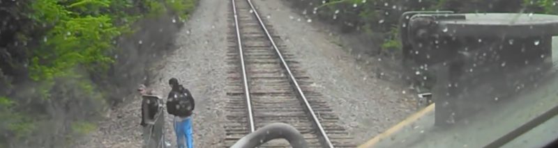 man walking close to railway track in front of an oncoming train