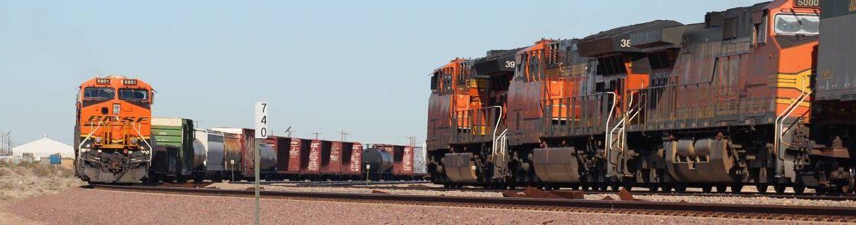 Two freight trains with orange locomotives head toward each other on separate tracks
