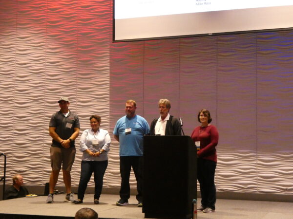 4 Graduates and the Director of LTAP stand on stage receiving applause for graduated the Advanced Roads Scholar program.